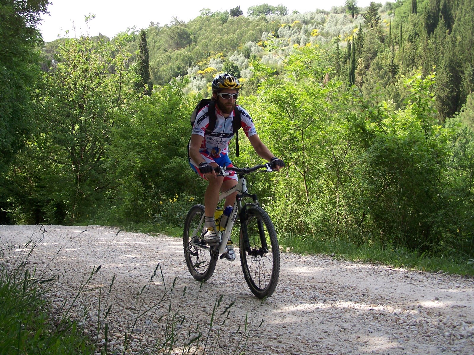 Ciclista in allenamento su strada sterrata tra le colline toscane